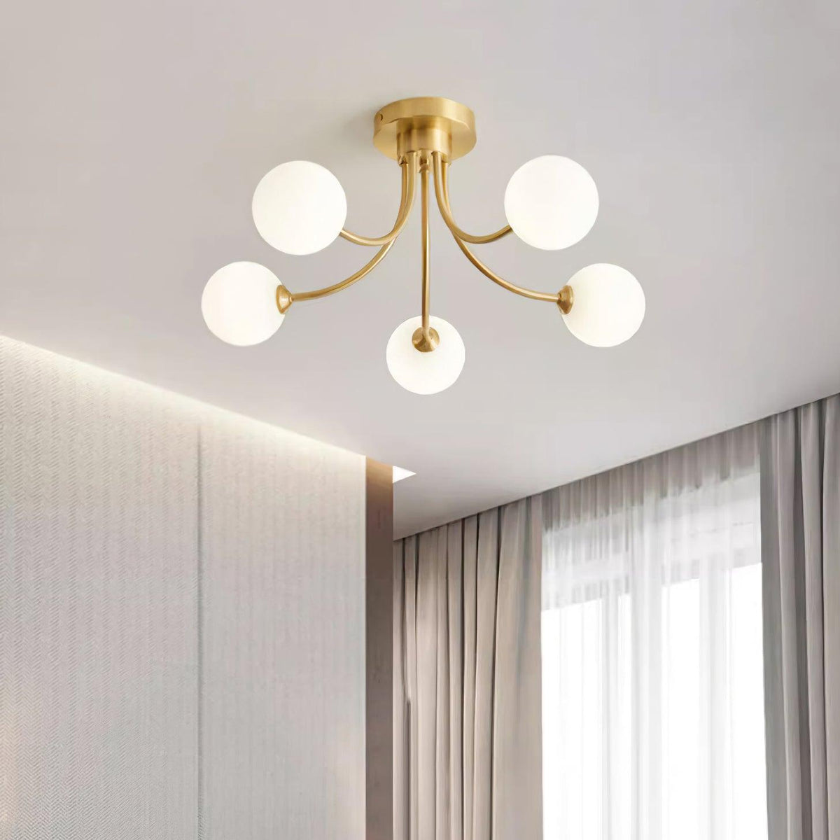 Loftslampe i messing med forgrenede arme og opale kugleskærme, moderne og elegant