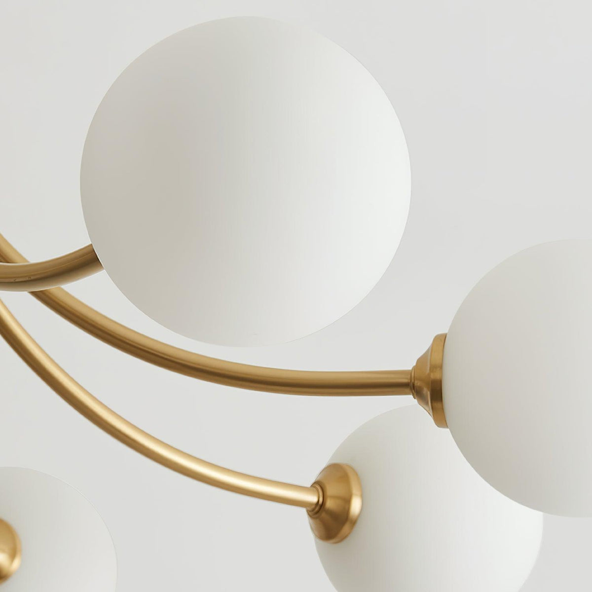 Loftslampe i messing med forgrenede arme og opale kugleskærme, moderne og elegant