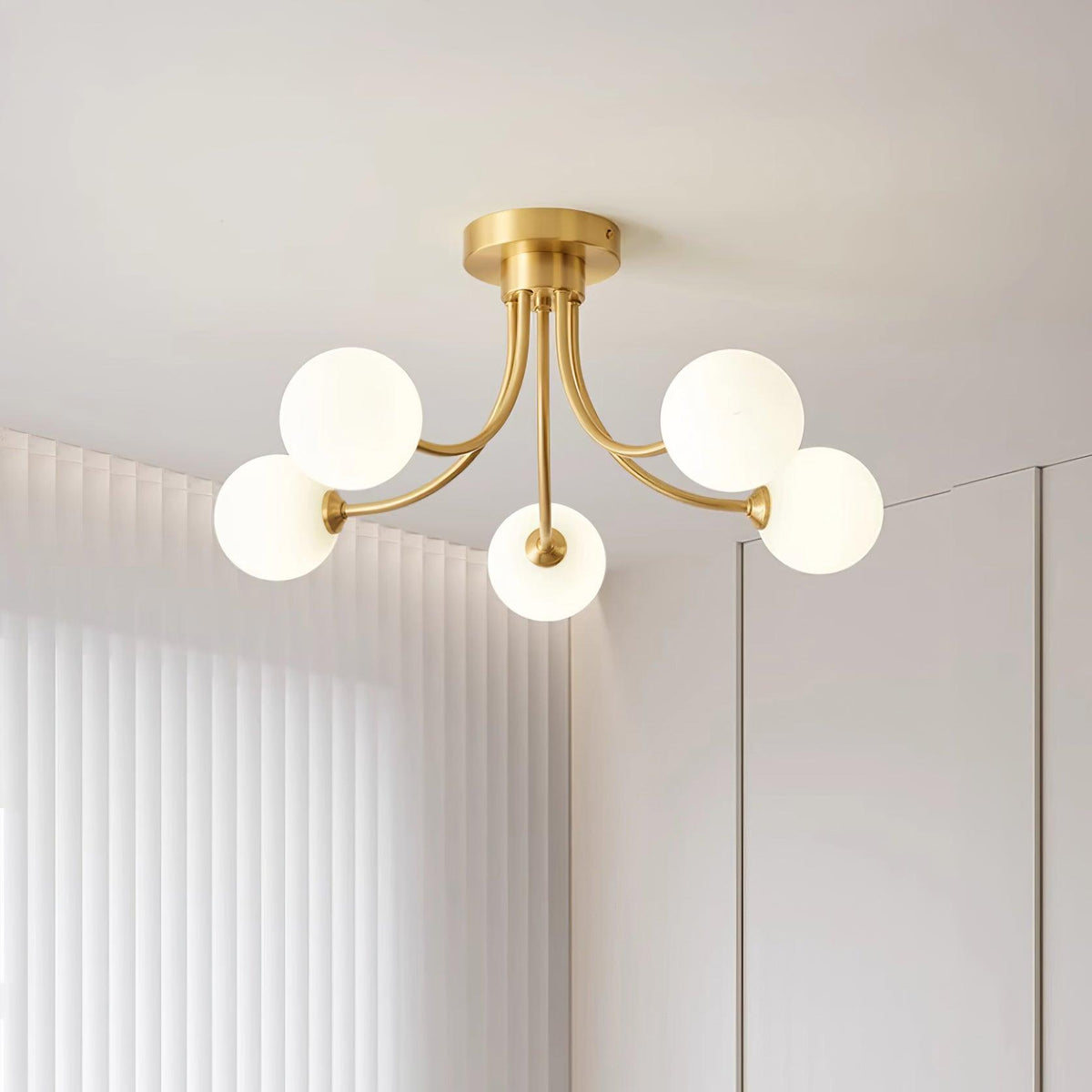Loftslampe i messing med forgrenede arme og opale kugleskærme, moderne og elegant